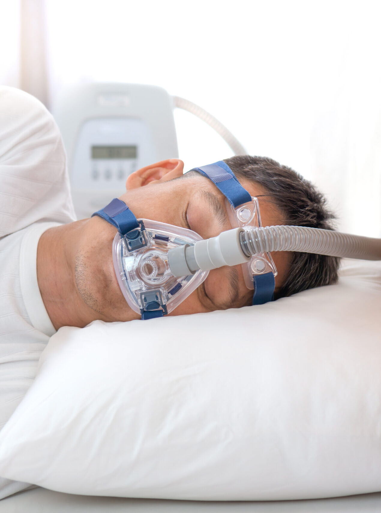 Man sleeping in bed wearing CPAP mask ,sleep apnea therapy Happy and healthy senior man sleeping deeply on his left side without snoring