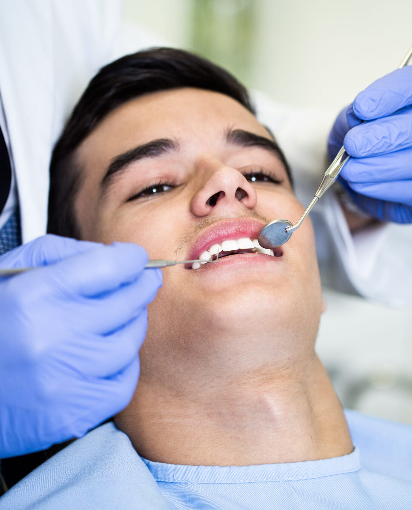Young attractive man receiving a dental treatment. Close up shot.