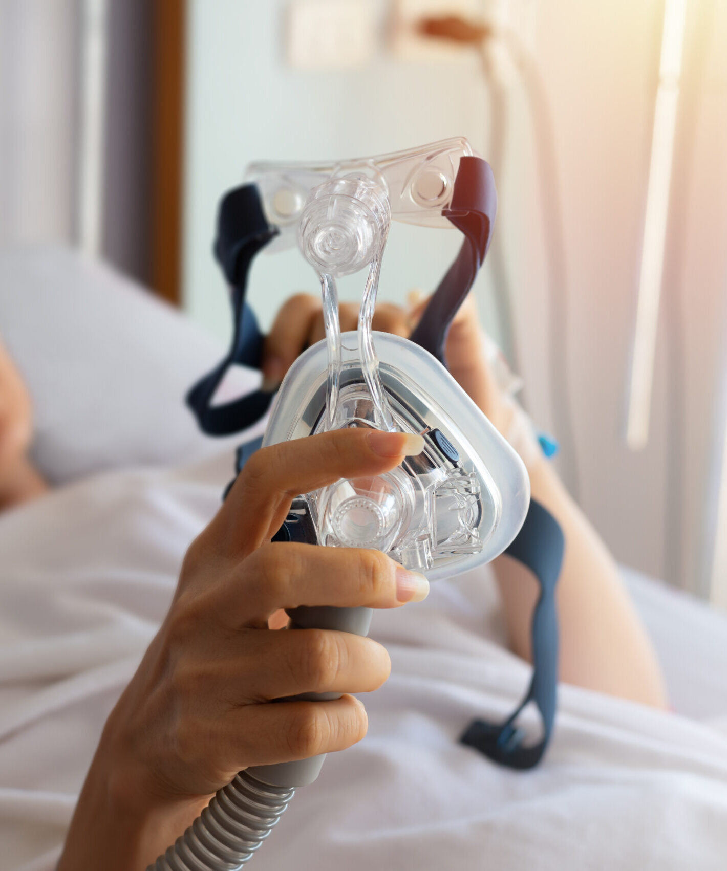 Senior patient woman hands holding Cpap mask lying in hospital room,selective focused. Obstructive sleep apnea therapy.