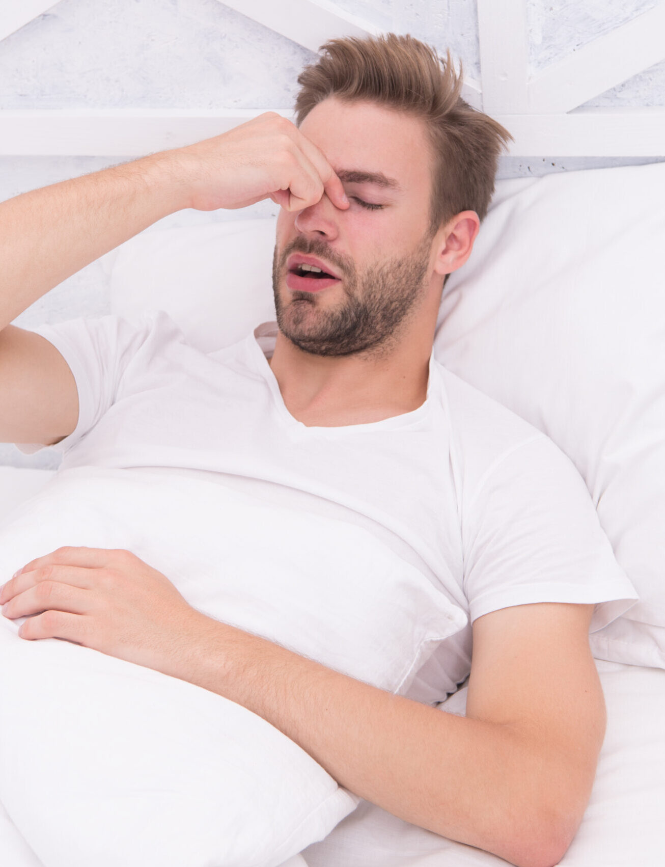 Snoring can increase risk headaches. Common symptom of sleep apnea. Causes of early morning headache. Migraine headaches. Sleep problems can lead to headaches in morning. Handsome man relaxing in bed.