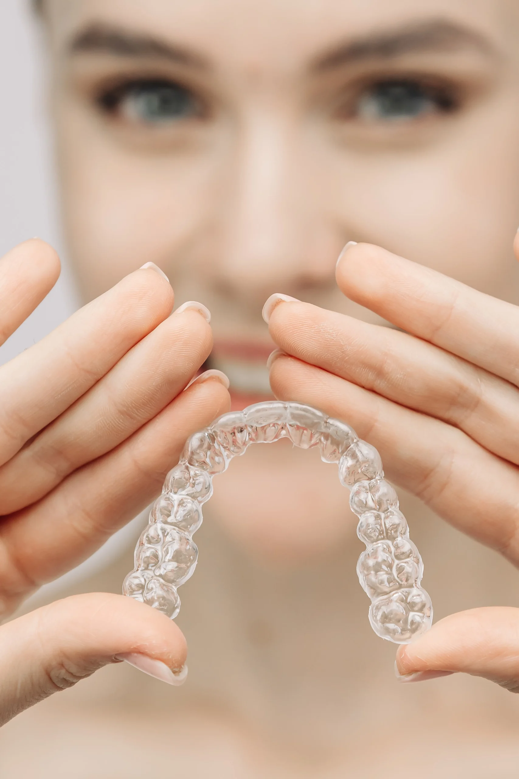 A woman uses an orthodontic silicone trainer for teeth correction. This mobile device highlights modern dental care methods and whitening systems, promoting a healthy and radiant smile.