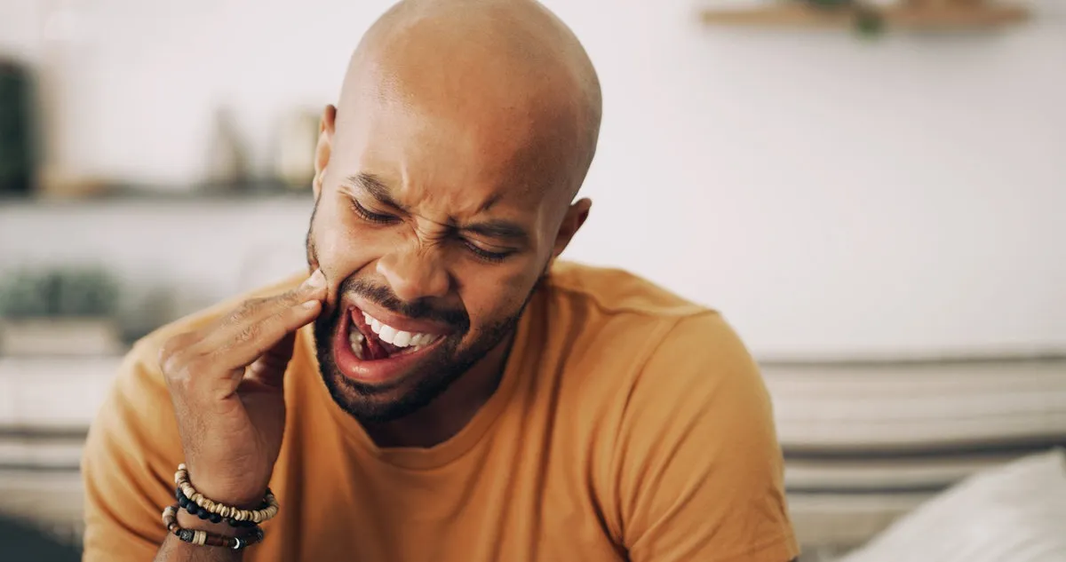 Toothache, sensitive and man in home with dental problem for cavity, gum disease or gingivitis. Pain, dentistry and male person with impacted wisdom teeth for tension, pressure or plaque in house