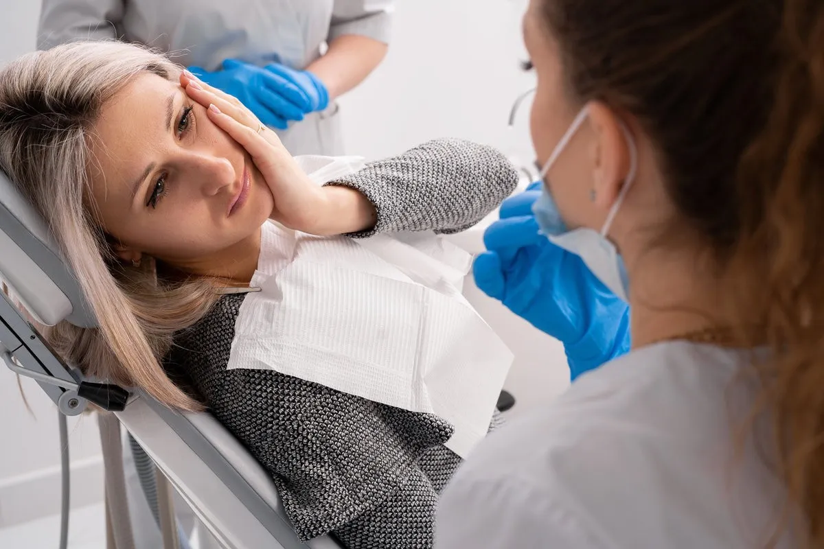 beautiful caucasian girl with toothache sits in a dental chair. Professional dentist helps his female patient in pain.painful treatment help. copy space.