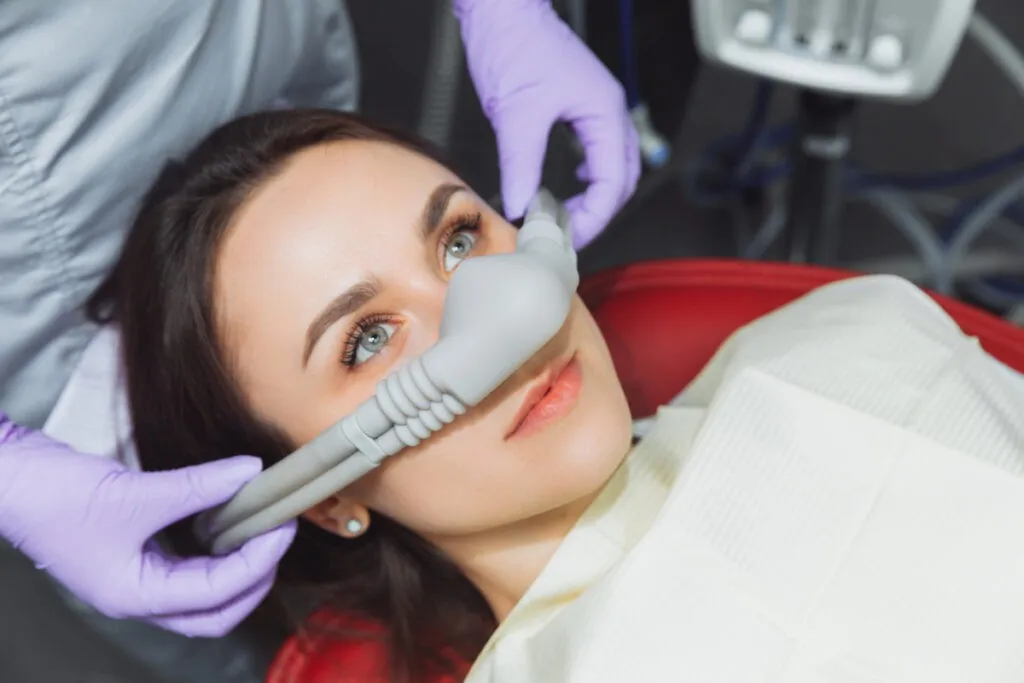 dentist puts inhalation sedative mask on his patient.