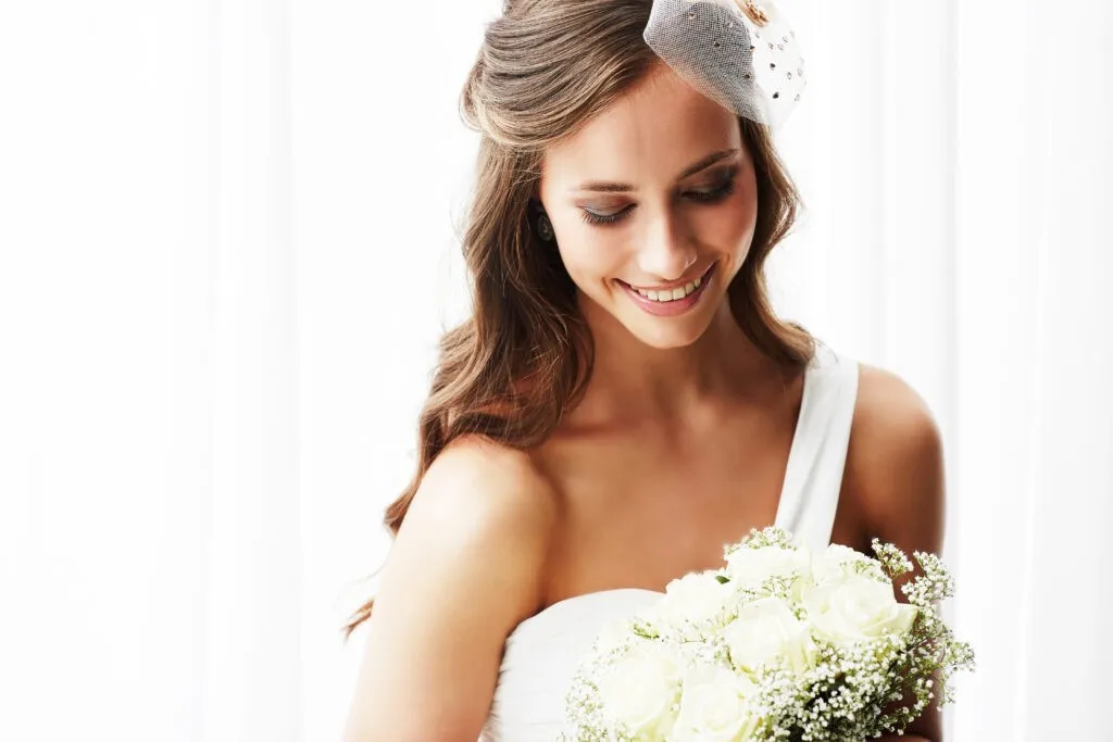 Young bride in wedding dress holding bouquet, studio shot