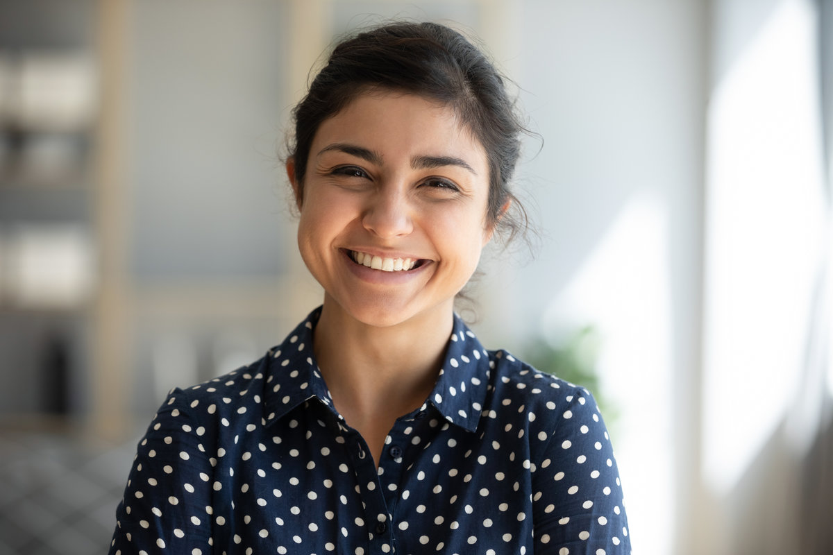 Cheerful beautiful indian girl student professional standing at home in office looking at camera, happy confident entrepreneur hindu lady laughing face posing alone, head shot close up view portrait