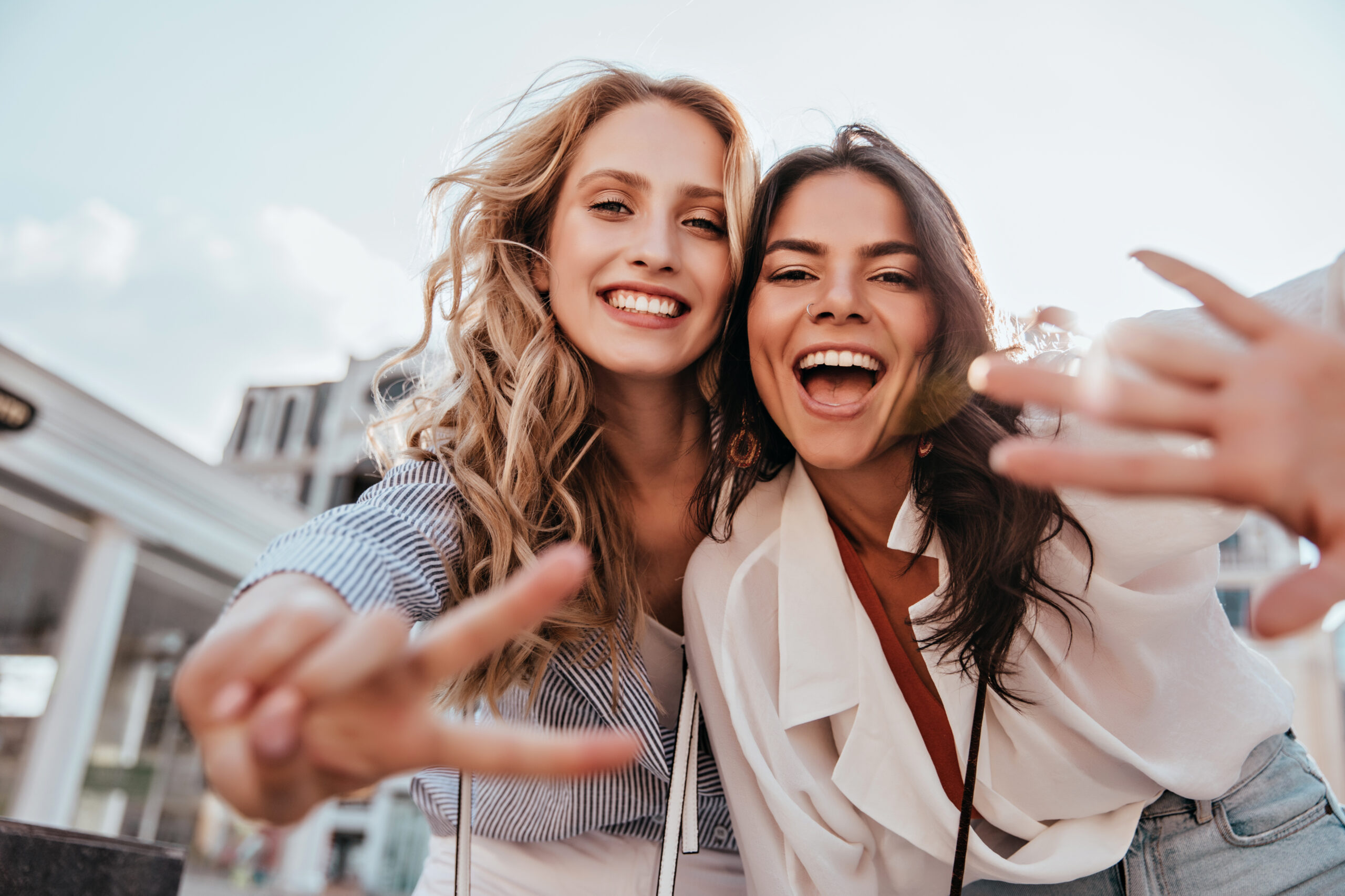 Lovable caucasian girls expressing positive emotions to camera. Outdoor photo of refined sisters posing on sky background.