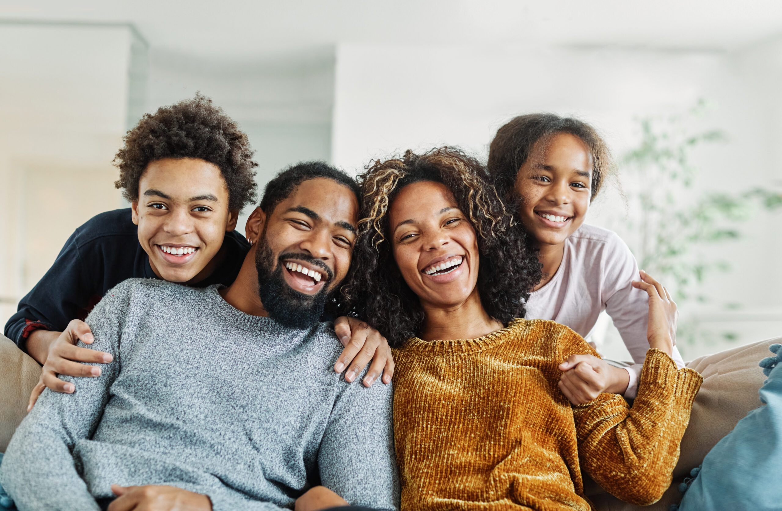 Portrait of a happy black family mother father and kids at home on couch