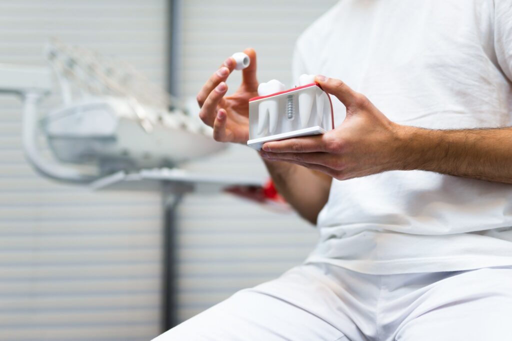 Dentist holding a dental implant model during a consultation at Rivers Dentistry