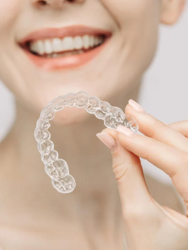 A woman with a beautiful smile and healthy teeth wears an orthodontic silicone trainer. This invisible aligner showcases a modern approach to orthodontics and confidence in her appearance.