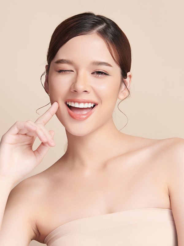 Beautiful smile young woman. White teeth on beige background,