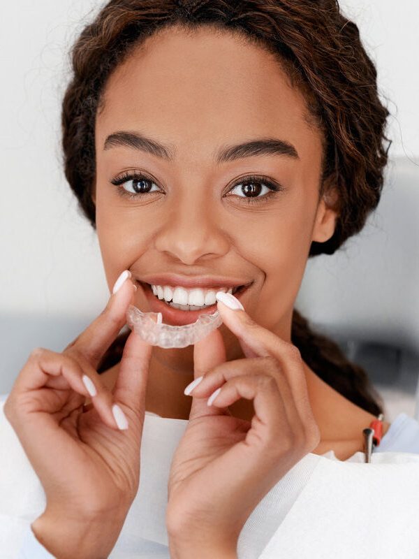 Dental Treatment Concept. Close up of young black woman holding invisible aligner, whitening tray, free space