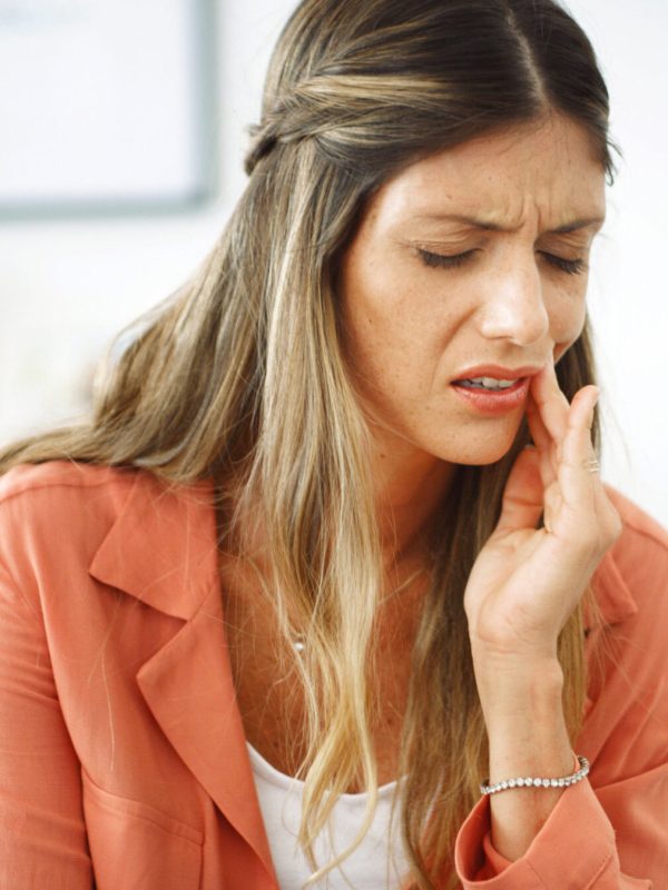 Woman, relax and pain from toothache at house with cavity, dental problem and gum infection. Female person, discomfort and touch cheek for sore gingivitis, root canal injury and tooth decay in lounge.