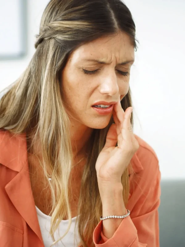 Woman, relax and pain from toothache at house with cavity, dental problem and gum infection. Female person, discomfort and touch cheek for sore gingivitis, root canal injury and tooth decay in lounge.