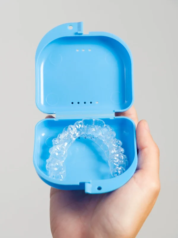 Transparent dental aligners in a case for storage and transportation are held by a woman's hand. Aesthetic and convenient correction of jaw bite. Copy space.