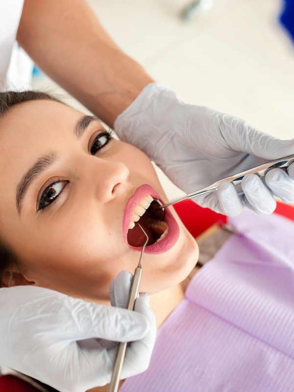 Beautiful girl treats teeth in dentistry.