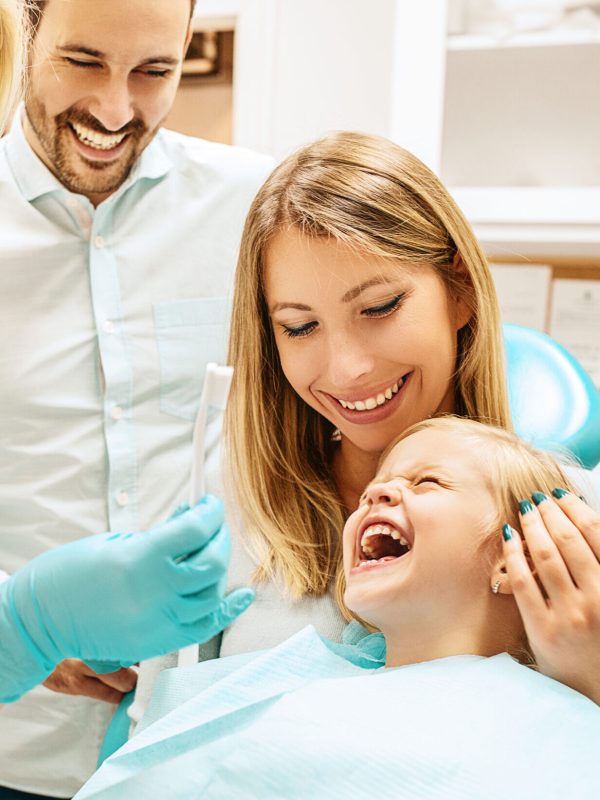 Dentist treating cute blonde child in his surgery.