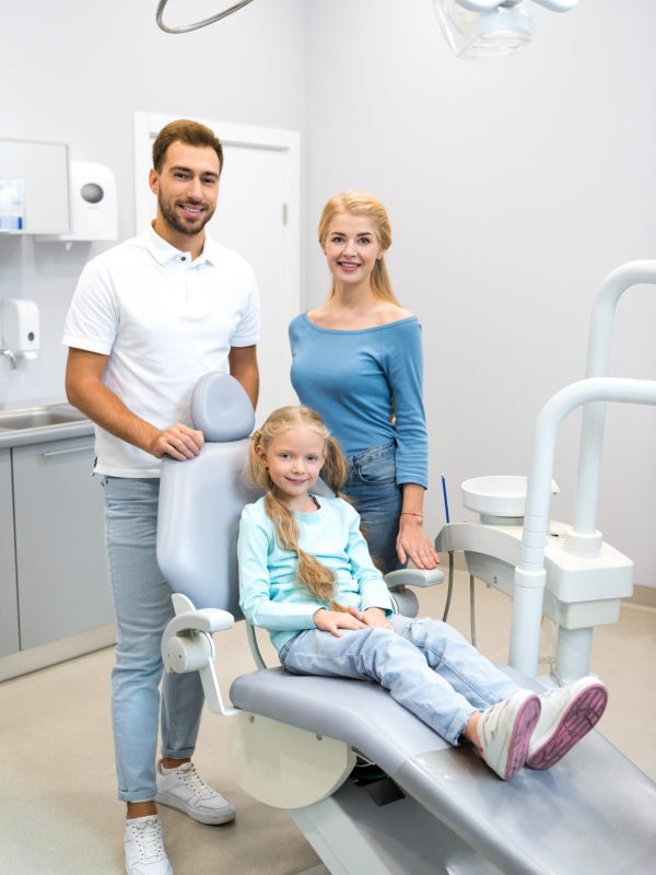 beautiful young family looking at camera at dentist office