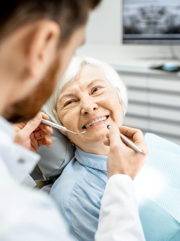 Elderly woman during the medical examination with male dentist in the dental office