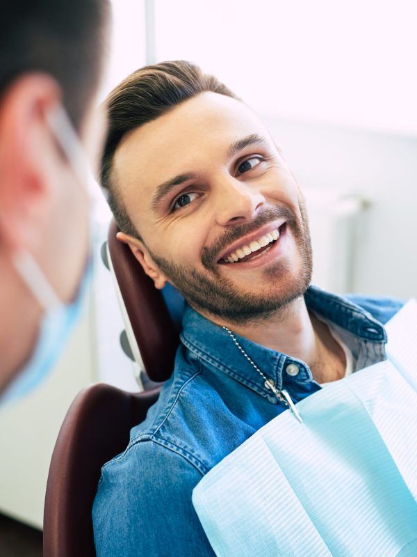 Pretty face mimic and a white smile of a nice man in a dental chair after getting a doctor’s treatment in a professional clinic.