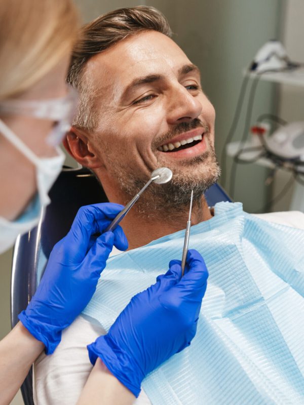 Image of a handsome happy young man sitting in medical dentist center.