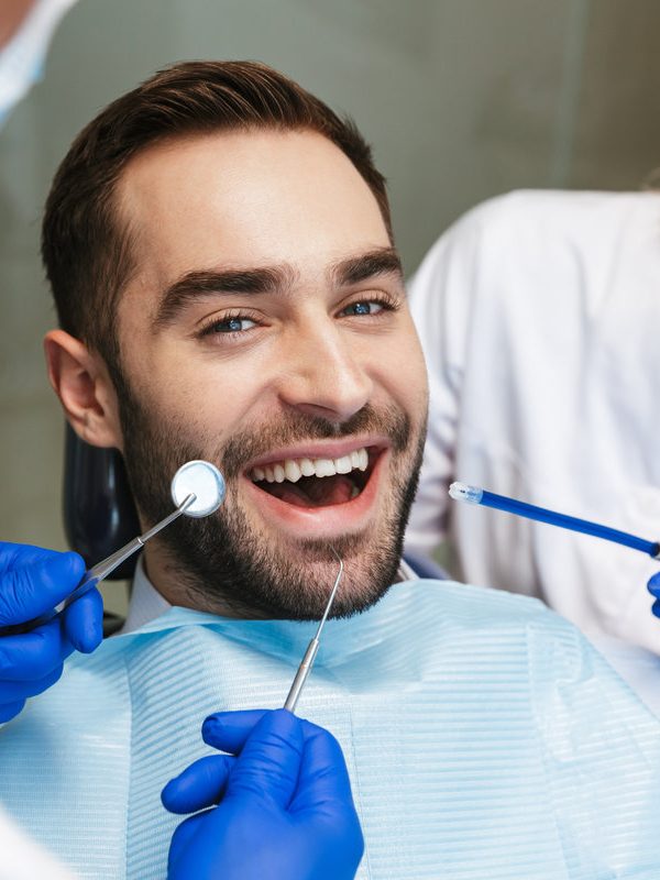 Image of a handsome happy young man sitting in medical dentist center. Looking at camera.