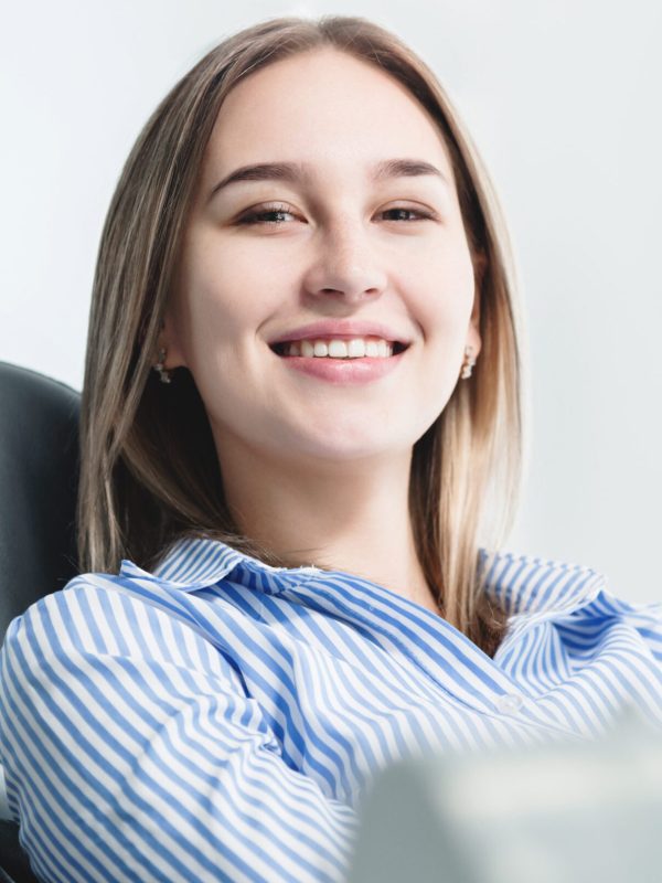 Portrait of an attractive smiling girl blonde in a dental chair. Happy customer dental cabinet.
