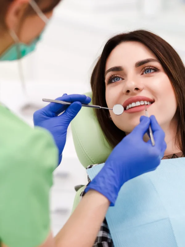 Beautiful young woman doing tooth examination in the dental office. Portrait of smiling girl on a dental chair in dentistry