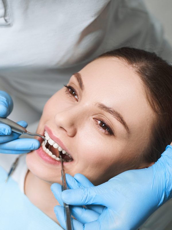 Young female is lying in dental chair during procedures for healing her teeth with equipment
