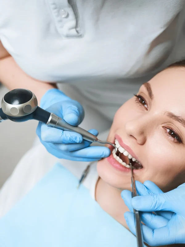 Young female is lying in dental chair during procedures for healing her teeth with equipment
