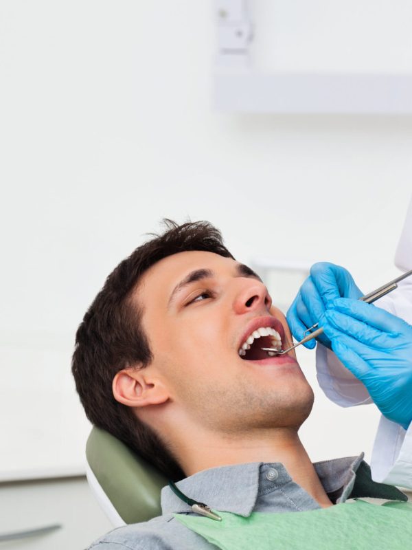 Female dentist examining a male patient at clinic