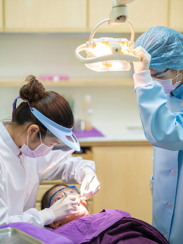 Portrait photo of Asian girl and Dentist wearing face mask and face shield checking up teeth healthy in Dental's office. Dental care, Medical care, Dental clinic, New normal concepts