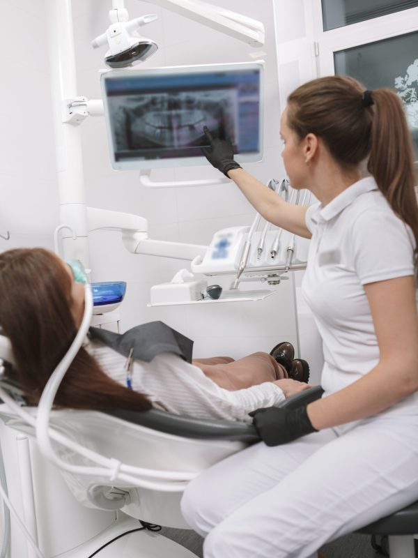 Vertical shot of a dentist explaining her patient dental x-ray scan on the screen, waiting for inhalation sedation to work
