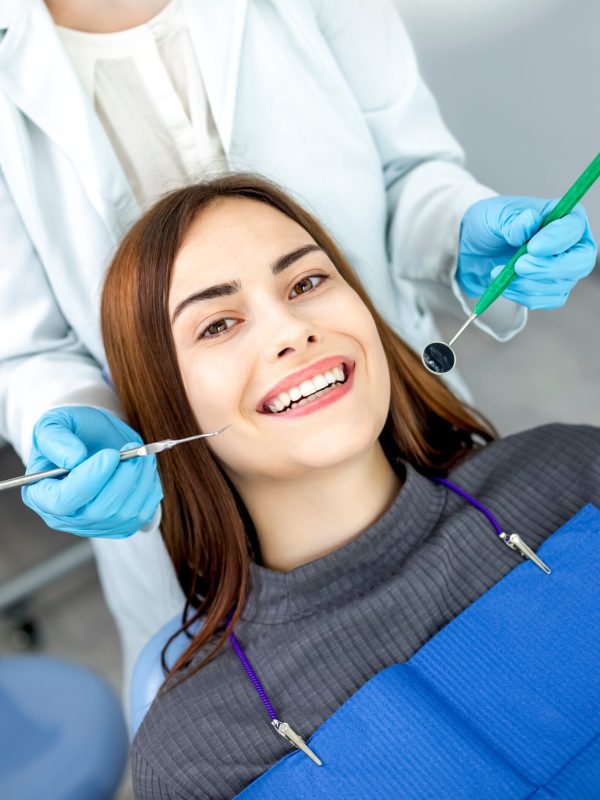 A woman patient sits in a dental chair at a dentist doctor's appointment. A girl with a beautiful smile and white even teeth.