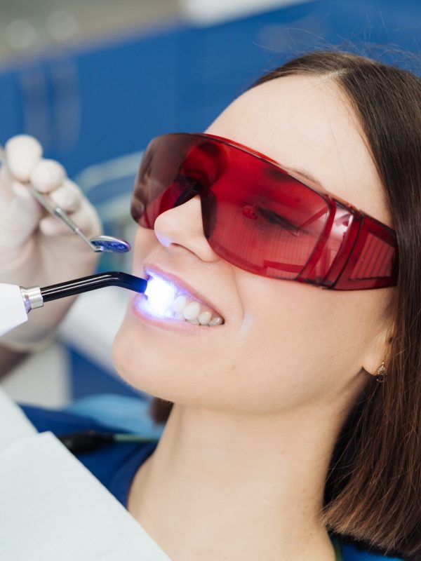 Close-up portrait of a female patient visiting dentist for teeth whitening in clinic