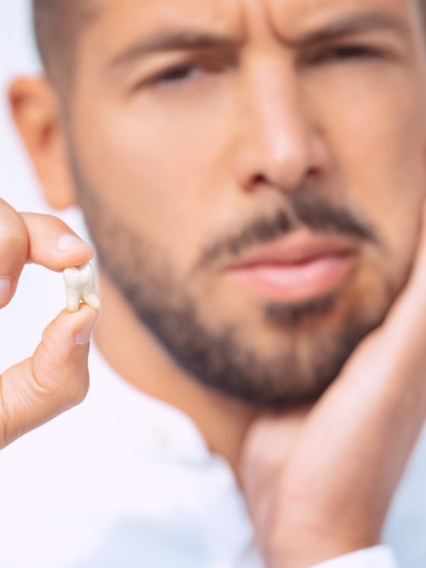 Man with extracted tooth after tooth removal surgery. Pain after tooth extraction. High quality photo