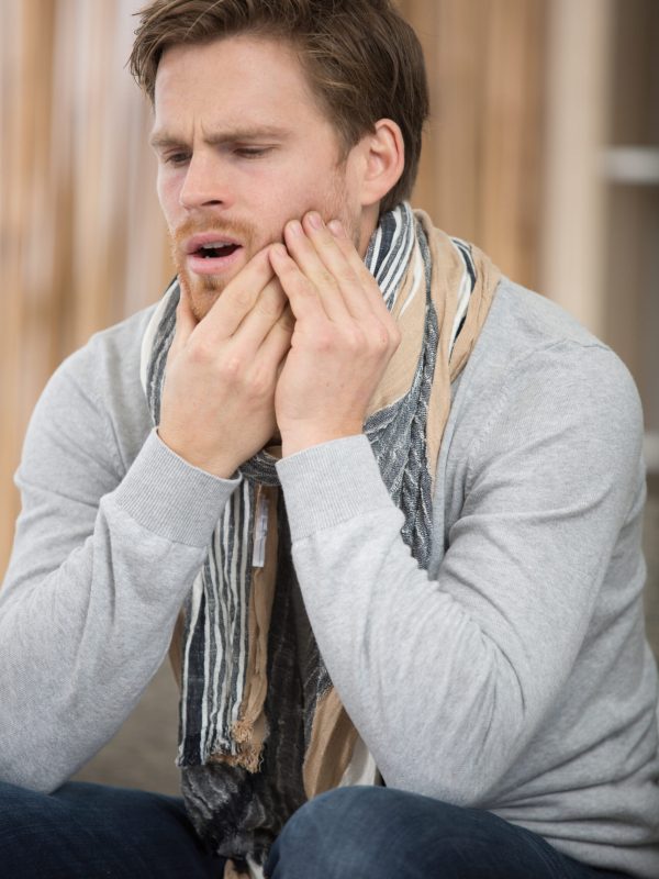 man holds his hand near the cheek toothache