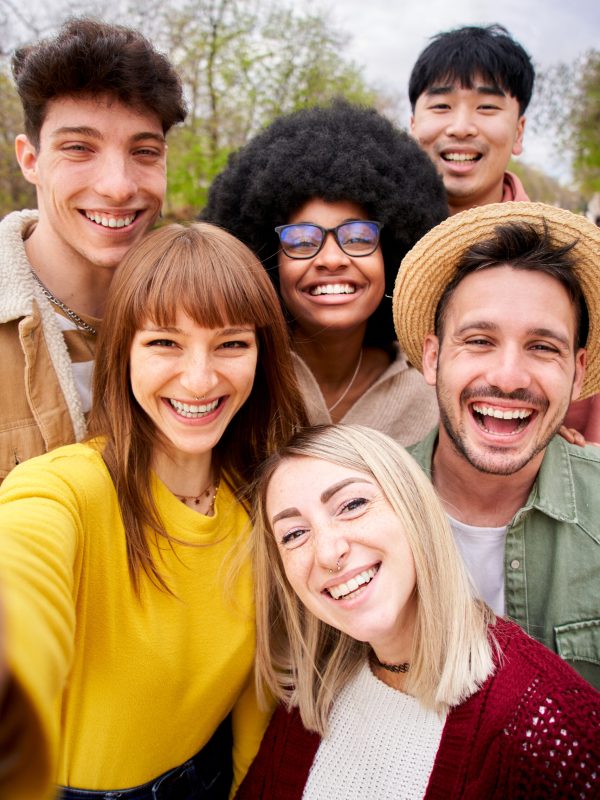 Vertical photo of large group of cheerful young friends taking selfie portrait outdoor.