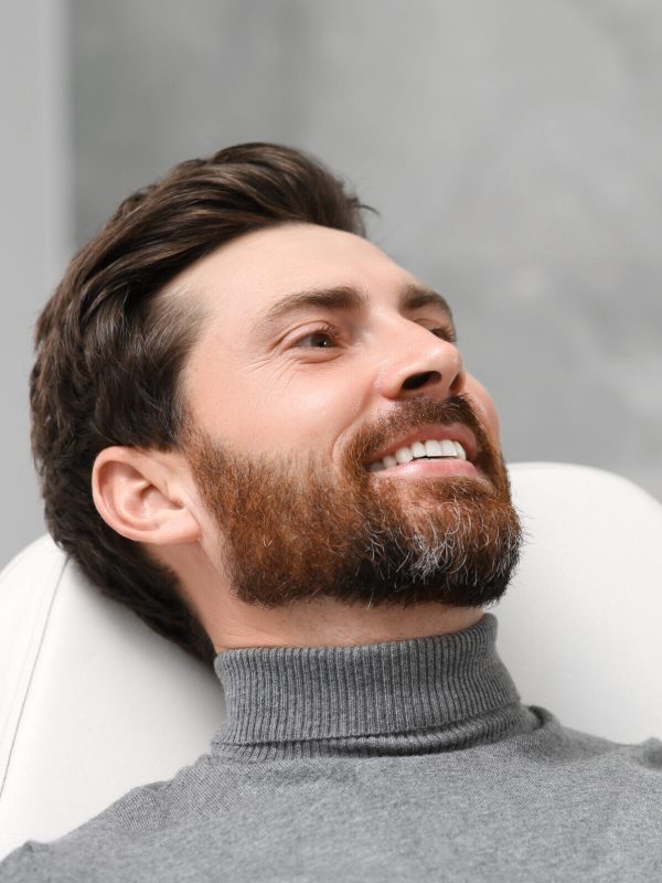 Man looking at his new dental implants in mirror indoors