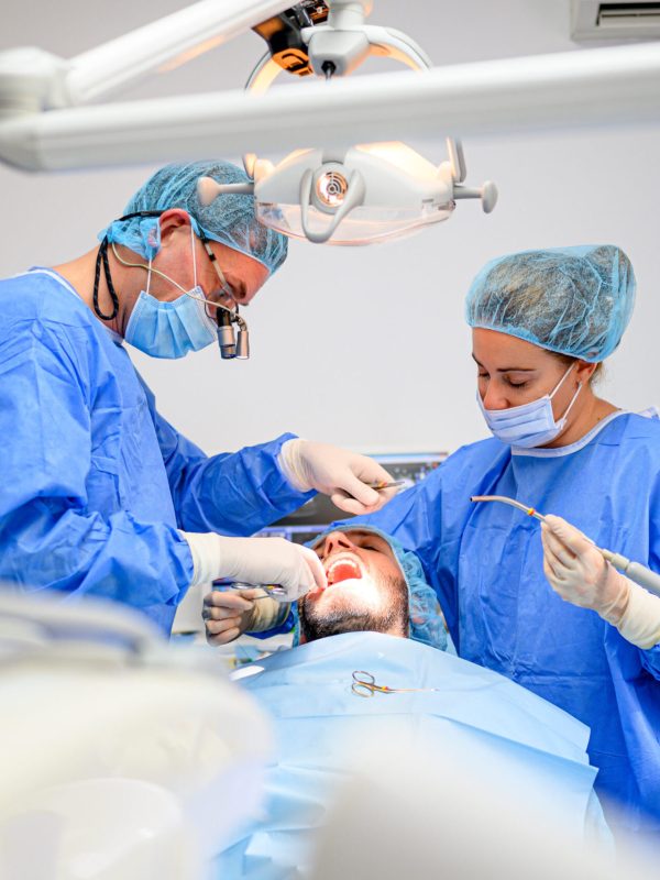 Dental surgeon and assistant work putting dental implant