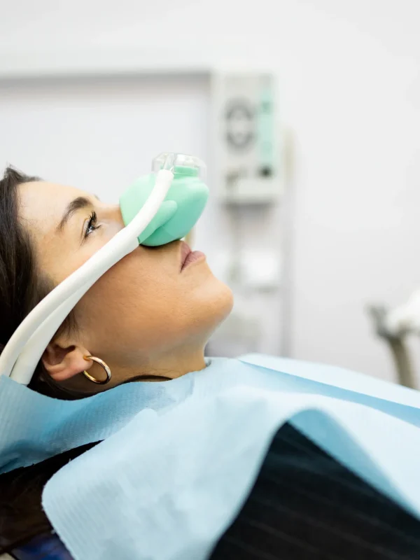 An adult woman sits in a dentist's office wearing a nasal mask to inhale nitrous oxide. Dentist fear concept. Feeling of relaxation with laughing gas. Visit a dentist with relaxation.