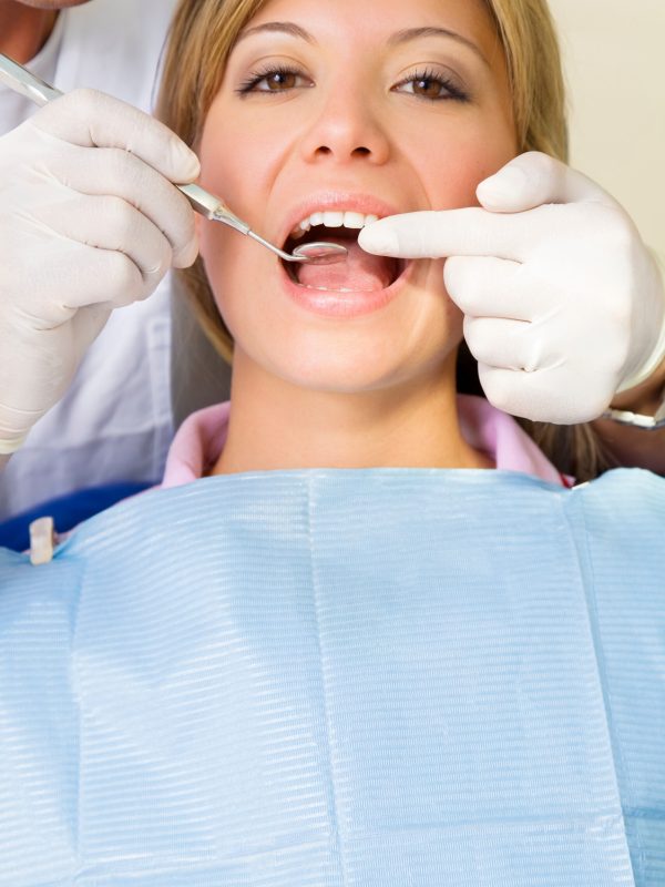 dentist using an angled mirror. Copy space. The focus is on woman's teeth