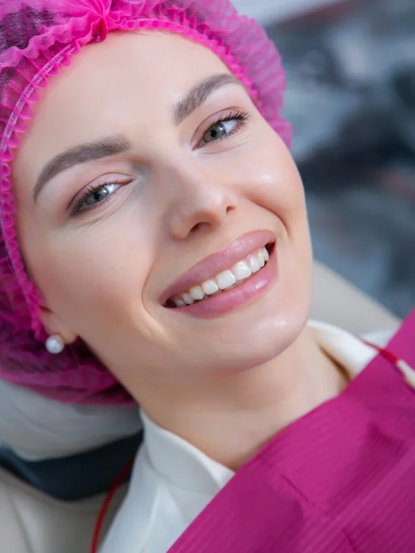 Closeup of female patient showing her beautiful white teeth while having treatment at dental clinic, dentist hands in rubber gloves holding dental tools