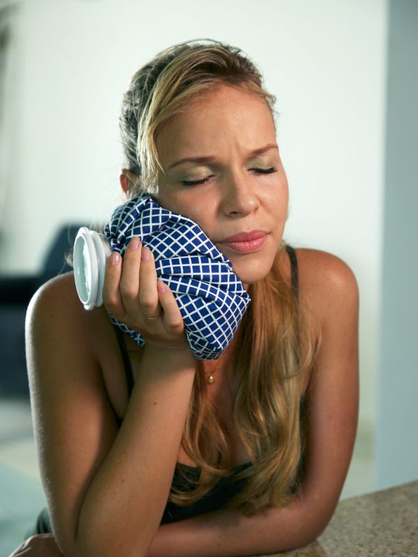 Young hispanic girl with tootache and dental problems, feeling pain and putting ice bag on mouth