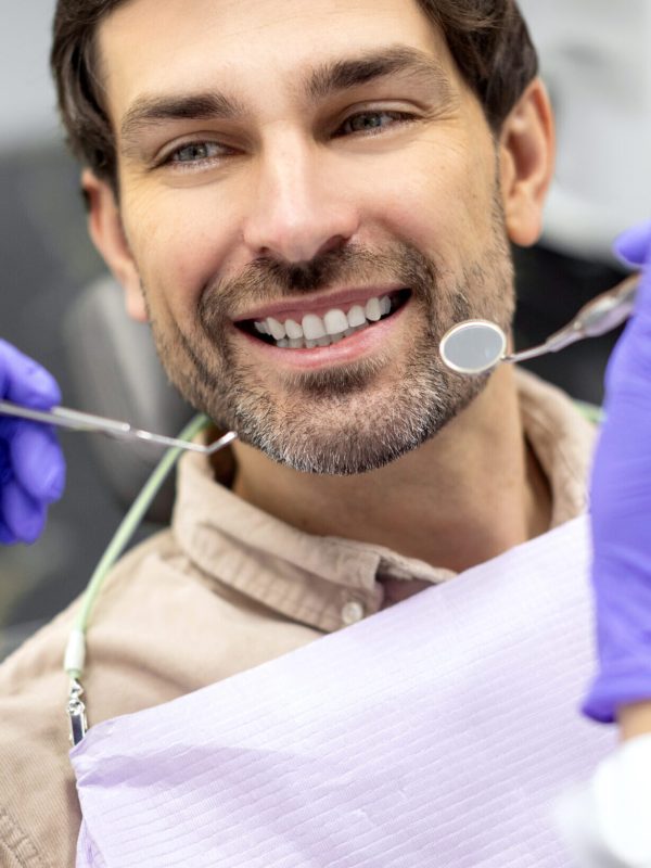 Closeup shot of dentist examining male patients teeth in dental clinic. Man having his teeth examined by female dentist