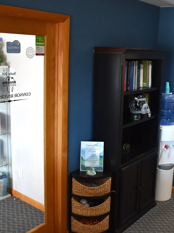 Rivers Dentistry office waiting area with product display cabinet, water cooler, and blue walls